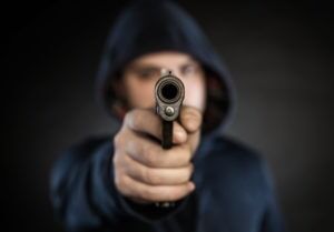Hooded figure pointing a handgun, illustrating the violent crimes defense cases handled by Simmrin Law Group
