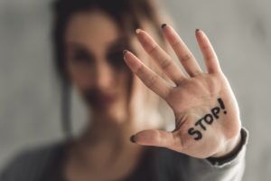 Woman holding up a hand marked STOP, illustrating the sex crimes defense cases handled by Simmrin Law Group